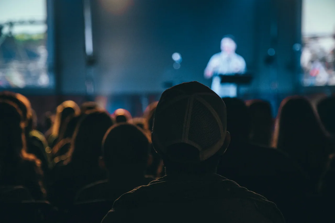 Audience watching a conference speaker on stage.